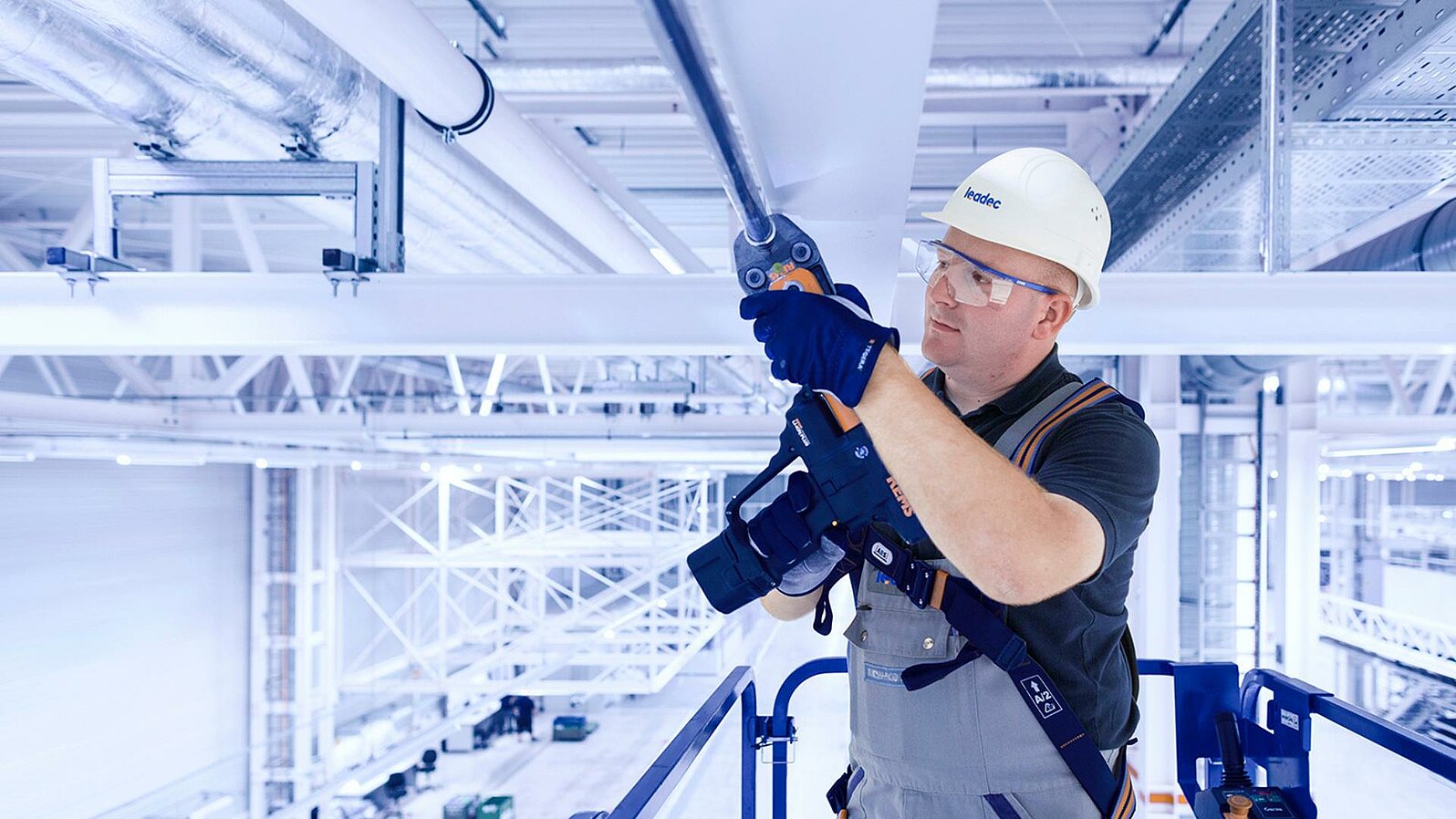 Leadec employee installing media supply on the ceiling of a factory.